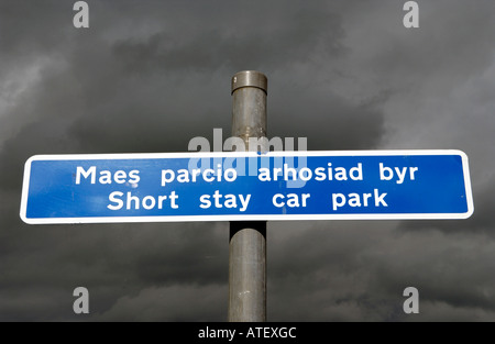 Langue Bilingue Anglais parking gallois signe sous un ciel gris foncé dans la ville de Dolgellau Gwynedd au nord du Pays de Galles UK Banque D'Images