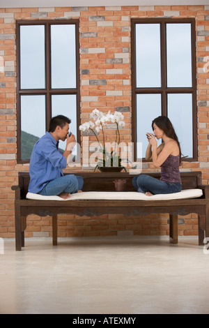 Portrait d'un jeune couple assis sur un canapé à boire le thé Banque D'Images