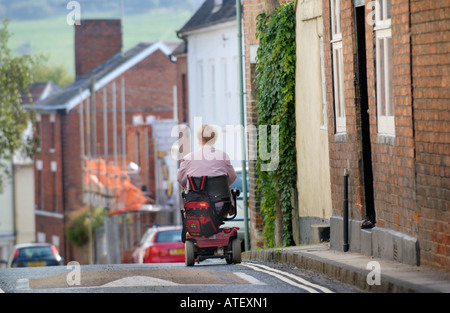 Femme âgée en fauteuil roulant motorisé sur route secondaire à Ludlow Shropshire England UK Banque D'Images