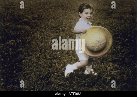 Image colorée à la main de 5yo boy running in short blanc chaussures et chapeau de paille Banque D'Images