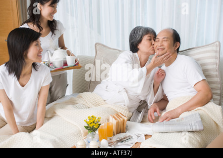 Young woman kissing un homme mûr en face de leurs deux filles Banque D'Images