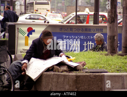 Paire de vieux mendiant sénile de la station de métro de l'homme s'asseoir une entrée lire journal comme voiture monde rendez-vous passez par Tokyo Japon Asie Orientale Banque D'Images