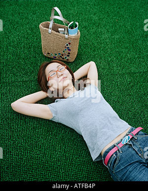Jeune femme couchée sur le gazon synthétique