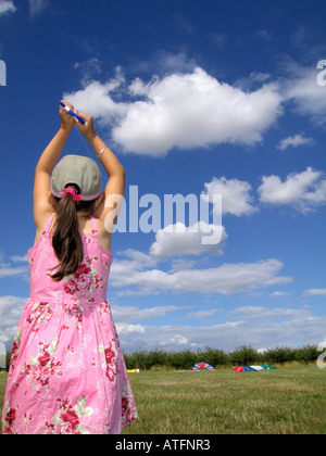 Young Girl flying kite sur fond de ciel bleu et nuages blancs moelleux Banque D'Images