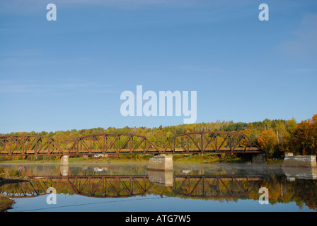 Image d'un pont ferroviaire sur une rivière calme avec toutes les couleurs de l'automne autour de Banque D'Images