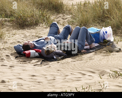 Couple laying in les dunes de sable profitant du soleil du printemps Banque D'Images