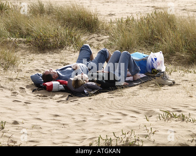 Couple laying in les dunes de sable profitant du soleil du printemps Banque D'Images