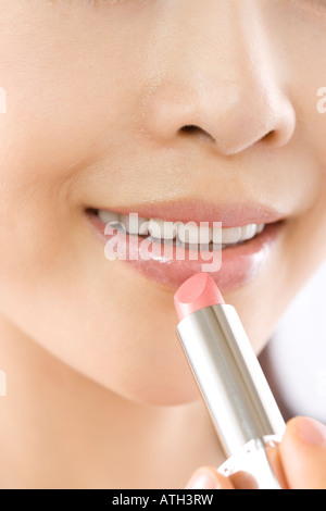 Young woman applying lipstick Banque D'Images