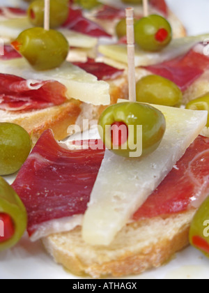 Style espagnol tapa de tranches de jambon iberico de bellota et fromage Manchego avec olives farcies poivrons pain croûté sur stonebaked. Banque D'Images