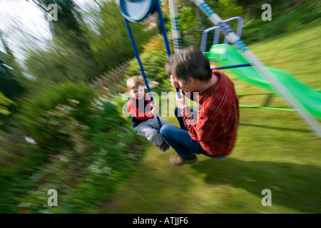 Jeune garçon de 3 ans avec papa on swing Banque D'Images