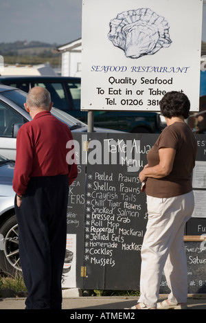 Les visiteurs DE WEST MERSEA PRÈS DE COLCHESTER ESSEX D'OEIL À UN MENU DE RESTAURANT DE FRUITS DE MER Banque D'Images