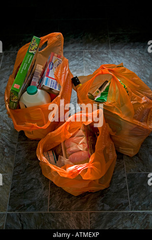 Sacs en plastique orange rempli de shopping sur un sol carrelé Ecosse, Royaume-Uni Banque D'Images