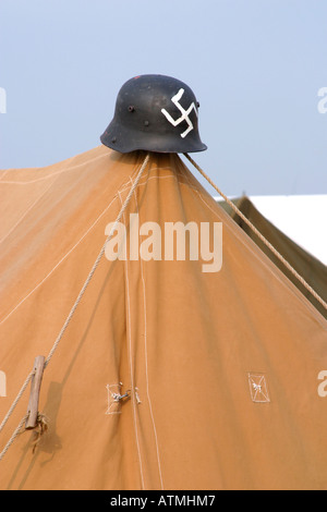 Casque allemand avec croix gammée peinte sur le devant sur piquet de tente Banque D'Images