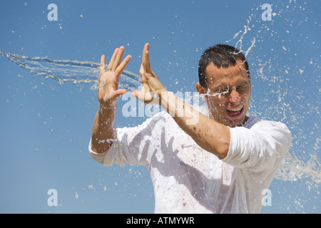 Man getting éclaboussé avec de l'eau contre un ciel bleu Banque D'Images