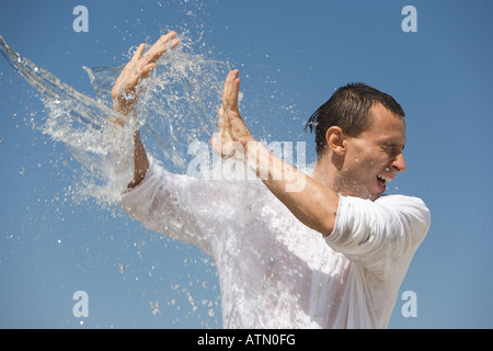 Man getting éclaboussé avec de l'eau contre un ciel bleu Banque D'Images