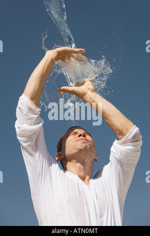 Man getting éclaboussé avec de l'eau contre un ciel bleu Banque D'Images