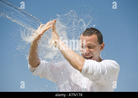 Man getting éclaboussé avec de l'eau contre un ciel bleu Banque D'Images