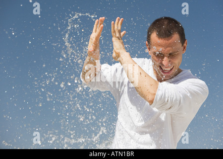 Man getting éclaboussé avec de l'eau contre un ciel bleu Banque D'Images