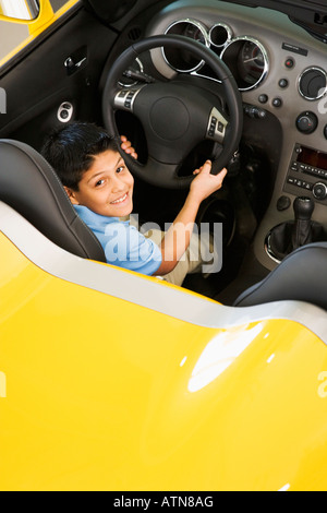 Hispanic boy sitting in new car Banque D'Images