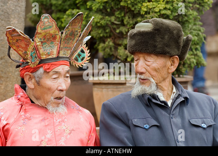 Prêtre Chaman Euroraum Naxi et vieux monsieur distingué assis sur un banc, Lijiang, Vieille Ville, Sifang Square, Yunnan, Chine Banque D'Images