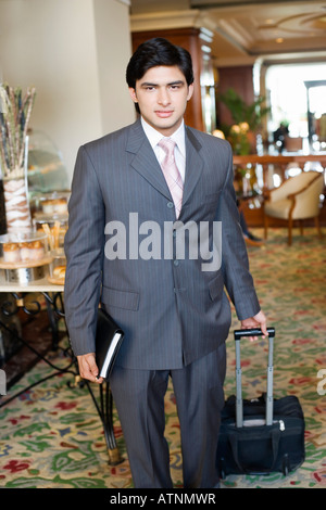 Portrait of a businessman pulling ses bagages dans un hall Banque D'Images