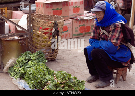 La Chine, le chinois Femme Naxi Vente de légumes à l'extérieur, marché traditionnel de Lijiang, Yunnan Province Banque D'Images