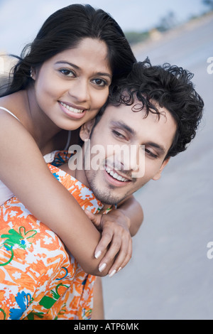 Portrait of a young woman riding piggyback sur un jeune homme souriant et Banque D'Images