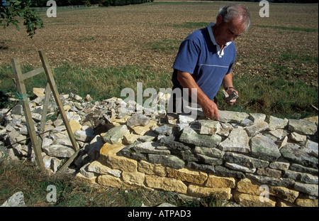 Un artisanat traditionnel l'édification d'un mur en pierre sèche dans les Cotswolds à partir de pierres locales avec un cadre en bois, Banque D'Images