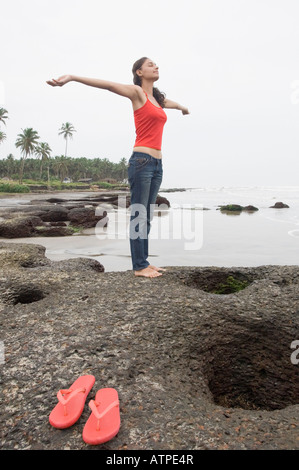 Jeune femme debout avec son bras tendus sur la plage Banque D'Images