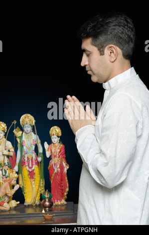 Portrait of a Mid adult man priant devant des figurines de Dieu Banque D'Images