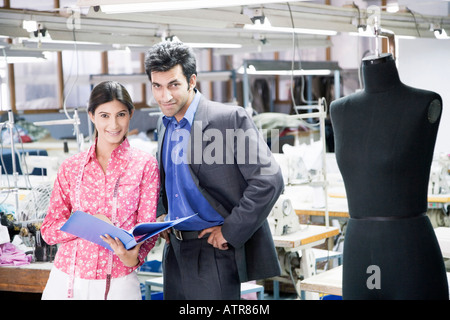 Portrait of a businessman standing avec un designer de mode féminine dans une industrie textile Banque D'Images