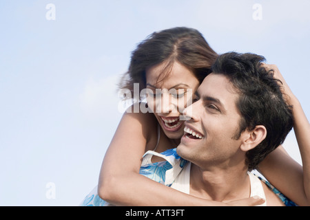 Close-up of a young woman riding piggyback sur un jeune homme souriant et Banque D'Images