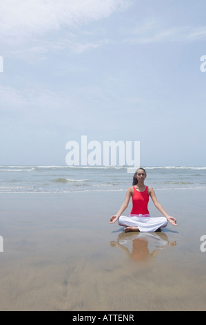 Jeune femme méditant sur la plage Banque D'Images