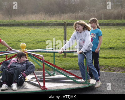 Enfants jouant sur un rond-point dans un parc Banque D'Images