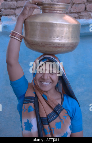 Young smiling woman portant une cruche d'eau sur la tête et vêtu d'un sari. Banque D'Images