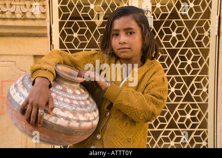 Jeune fille portant une cruche d'eau et, debout devant une porte ouvragée. Banque D'Images