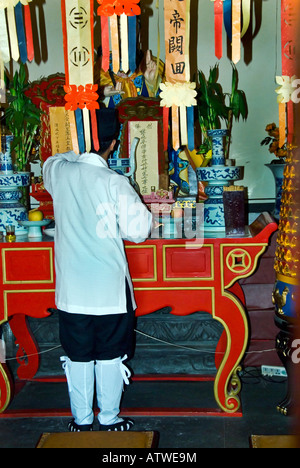 Beijing Chine, moine dans l'ancien temple taoïste colorés dans 'Stre financière-et' Salon priant à l'intérieur à l'autel décoré Banque D'Images