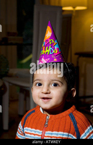 Un an baby boy wearing hat cone joyeux anniversaire Banque D'Images