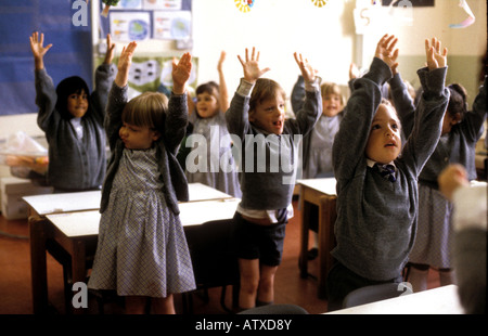 Les enfants d'âge maternelle dans le sud de Londres, l'école préparatoire debout, les bras élevés d'étirement Banque D'Images