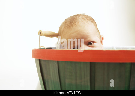 Un adorable bébé sort d'un panier avec un look sceptique. Banque D'Images