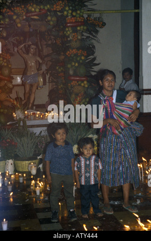 Femme avec enfants se tenant dans l'église remplie de fumée d'encens à San Sebastian pour Retalhuleu Guatemala célébrations festival Banque D'Images