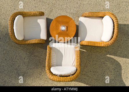 Des horizontales close up de trois chaises en osier vide et une table basse en bois à l'extérieur, au soleil Banque D'Images