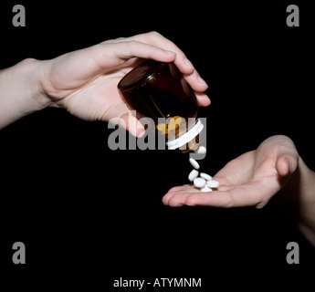 Un woman pouring pills à partir d'une bouteille. Banque D'Images