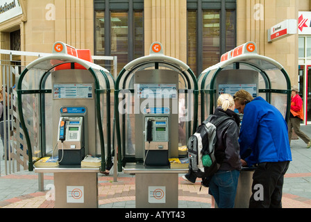 Couple utilisant des téléphones publics de style ancien Hobart Tasmanie Australie Banque D'Images