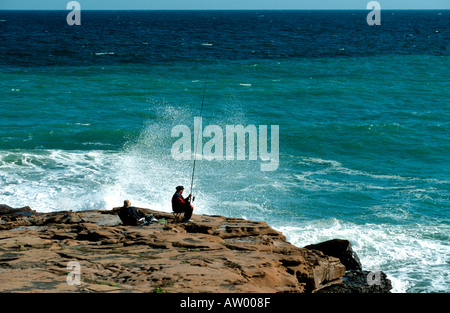 Pêcheur sur les rochers à Praia da Luz Algarve Portugal Banque D'Images
