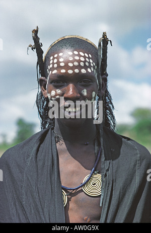 Jeune homme Masai après la circoncision vêtu de noir Shuka visage blanc peinture et bobines en laiton Tanzanie Afrique de l'Est Banque D'Images