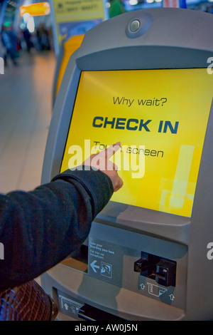 Femme à l'aide de l'auto-vérification dans le terminal avec écran tactile sur l'aéroport de Shiphol, Pays-Bas Banque D'Images