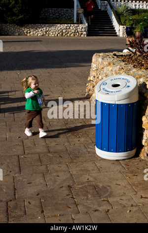 Petit Enfant femelle plaçant la bouteille dans une corbeille Banque D'Images