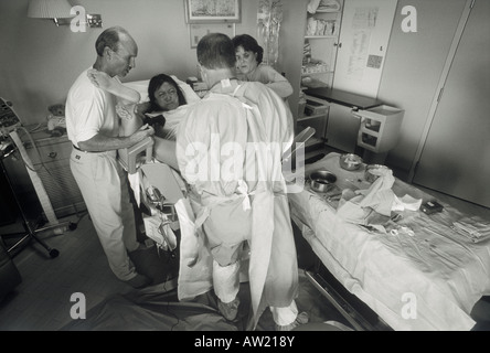 Médecin et l'infirmier et mari aidant avec la naissance de bébé dans la salle d'accouchement de l'hôpital Banque D'Images