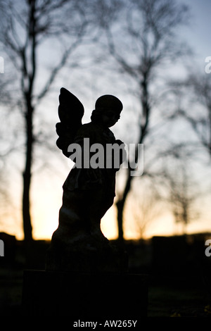 Silhouette d'ange pierre tombale dans un cimetière au lever du soleil. UK Banque D'Images